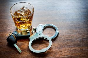 glass of alcohol next to handcuffs and keys