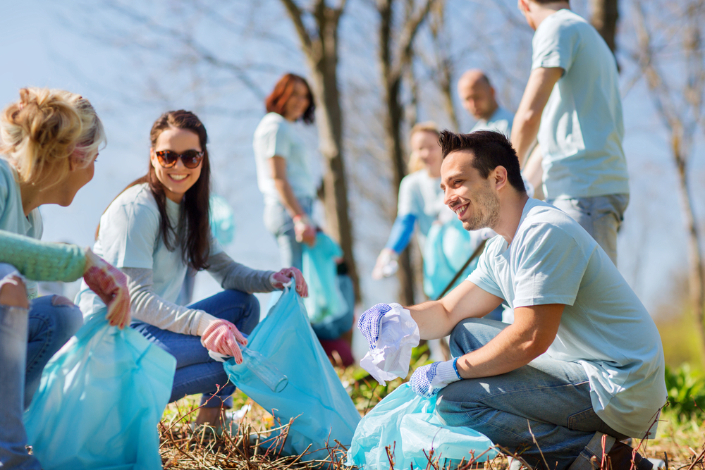 volunteers with garbage bags cleaning park area