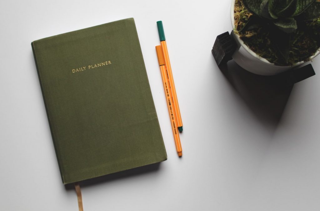 dark green planner next to two pencils